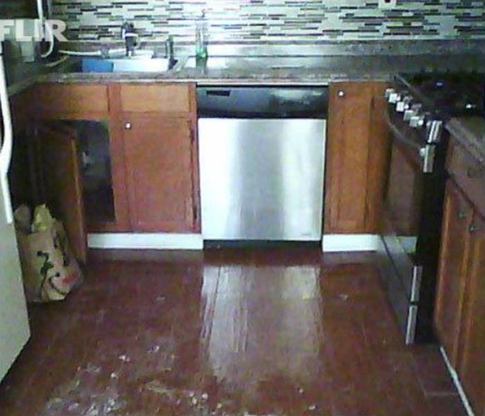 Water soaked kitchen floor and cabinets after a dishwasher malfunction